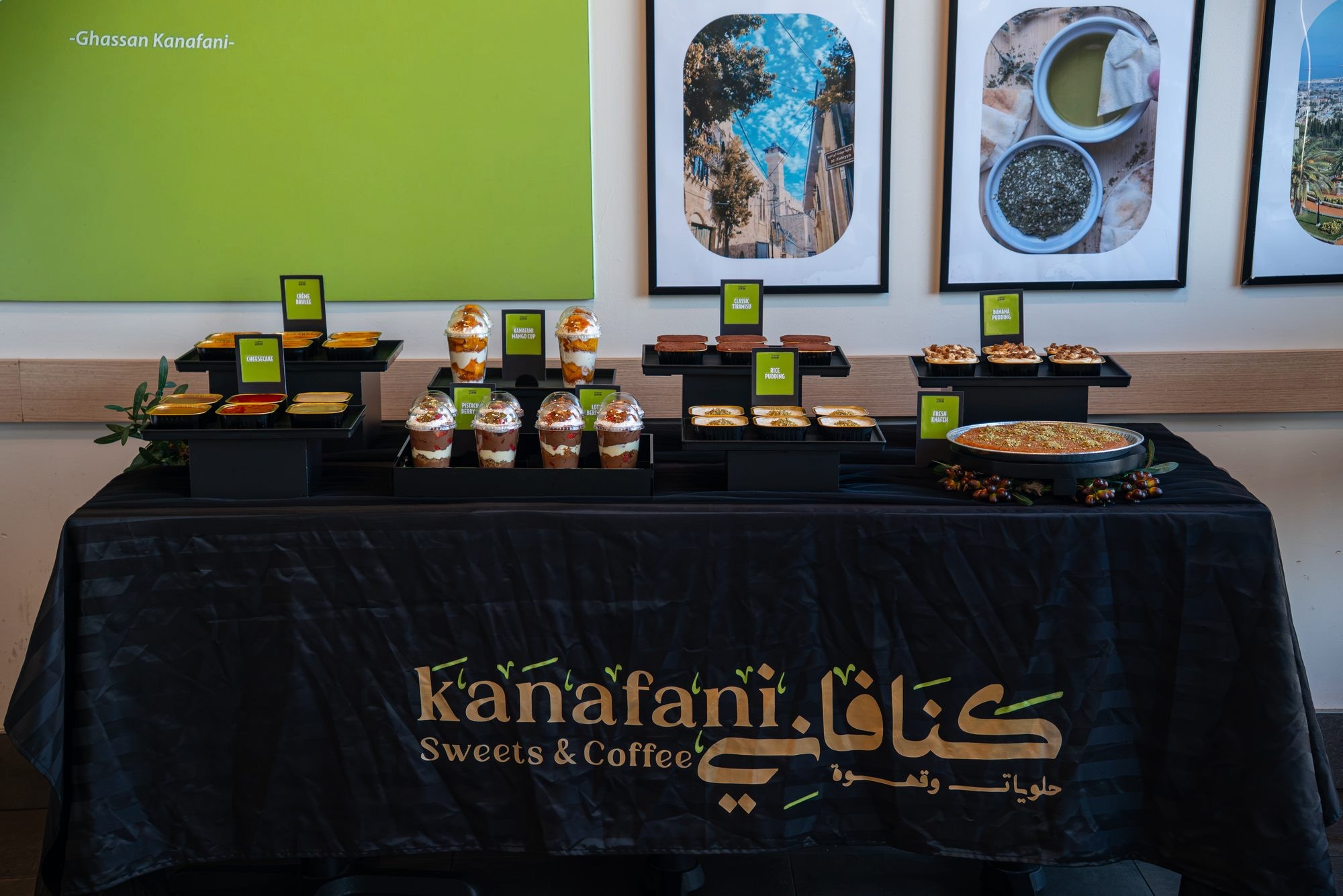 The stepped dessert display, front view — trays of Knafeh, cups and sweets on black cloth
