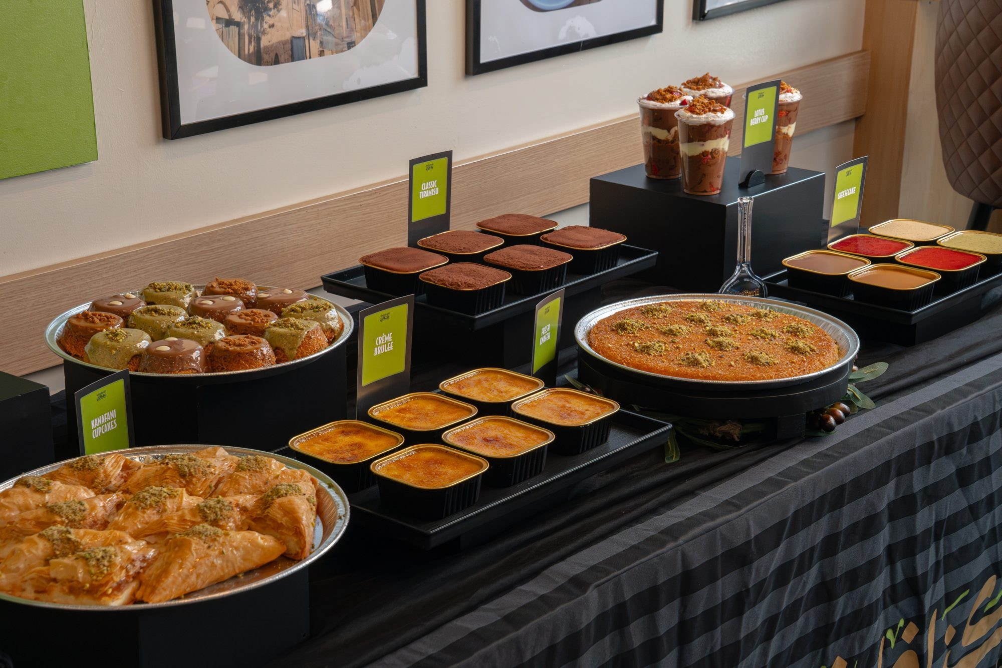 The dessert display photographed on the diagonal — trays of Knafeh, cups and bars in warm light